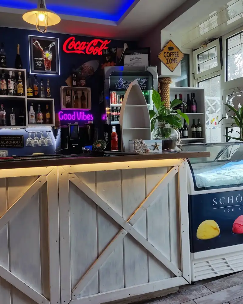 Bar z białymi deskami, lodówką z lodami i neonem