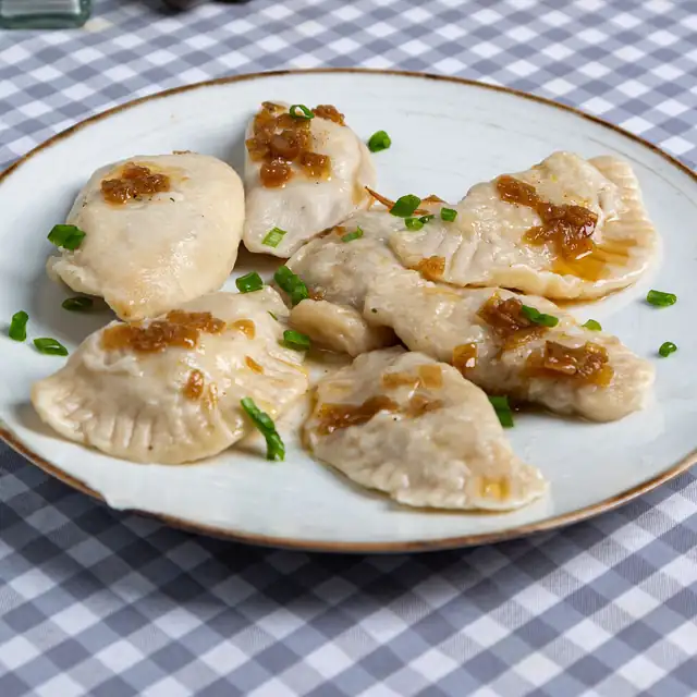 Domowe pierogi ze smażoną cebulką na białym talerzu