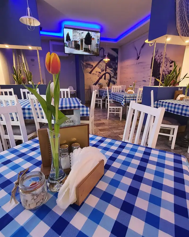 Sala ze stolikami w niebiesko-białą kratkę i tulipanem na stole